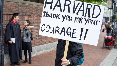 Ein Unterstützer der Harvard University mit einem Schild außerhalb des Campus.