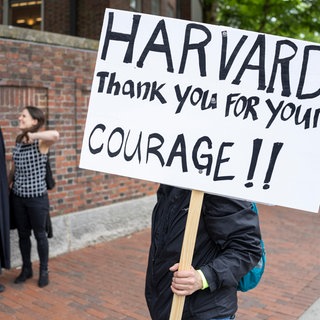 Ein Unterstützer der Harvard University mit einem Schild außerhalb des Campus.