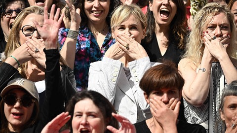 Schauspielerinnen halten Hand vor den Mund aus Protest