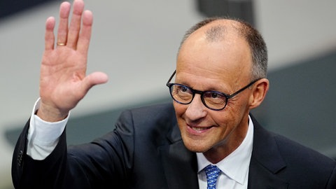 Der designierte Bundeskanzler Friedrich Merz (CDU) winkt im Bundestag vor der Kanzlerwahl.