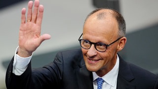 Der designierte Bundeskanzler Friedrich Merz (CDU) winkt im Bundestag vor der Kanzlerwahl.