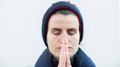 Frau mit gefalteten Händen und geschlossenen Augen