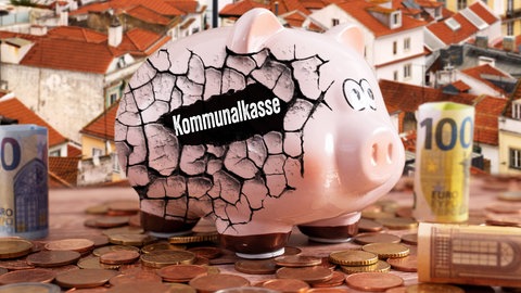 Ein rissiges Sparschwein mit der Aufschrift Kommunalkasse steht auf Münzen vor einem Stadthintergrund symbolisch für klamme Kommunen