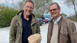 Wolfgang Metzger (links, 1. Kriminalhauptkommissar im Polizeipräsidium Karlsruhe) und Rüdiger Rehring (rechts, ehem. Oberstaatsanwalt in der Staatsanwaltschaft Karlsruhe) mit der Tatwaffe (Stein) des Mordes der Karlsruher Grünenpolitikerin Aune Riehle 