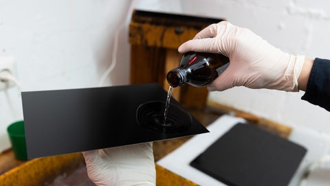 Beschichtung mit Kollodium wird über eine alte Platte für eine Plattenkamera geschüttet