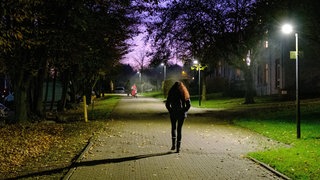 Frau läuft im Dunkeln allein auf der Straße.
