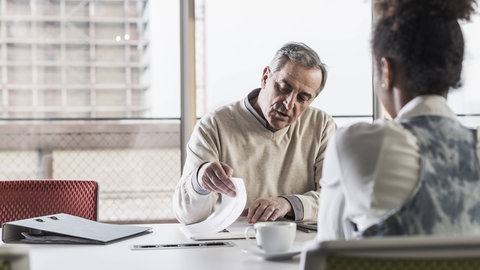 Bewerbungssituation: Ein skeptischer Mann sitzt einer schwarzen Frau gegenüber