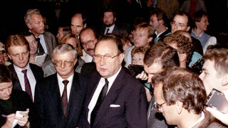 Außenminister Hans-Dietrich Genscher (rechts) und der Kanzleramtsminister Rudolf Seiters (links) von Reportern in der deutschen Botschaft in Prag umgeben