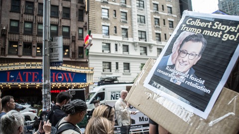 Protestierende Person mit Plakat für Stephen Colbert bei einer Demonstration in New York City am 21. Juli 2025 – gegen die angekündigte Absetzung seiner Late-Night-Show durch CBS.