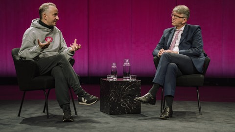Der Satiriker Jan Böhmermann im Gespräch mit Kulturstaatsminister Wolfram Weimer im Haus der Kulturen der Welt im Rahmen der Ausstellung „Die Möglichkeit der Unvernunft“.