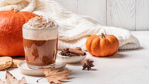 Pumpkin Spice Latte mit Kürbissen, Gewürzen und Herbstlaub