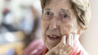 Nahaufnahme, authentisches, ungestelltes Porträt einer über 90 Jahre alten, dementen, an Alzheimer erkrankten Seniorin im Seniorenheim