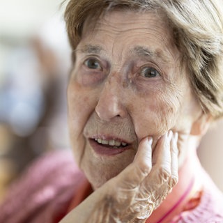Nahaufnahme, authentisches, ungestelltes Porträt einer über 90 Jahre alten, dementen, an Alzheimer erkrankten Seniorin im Seniorenheim