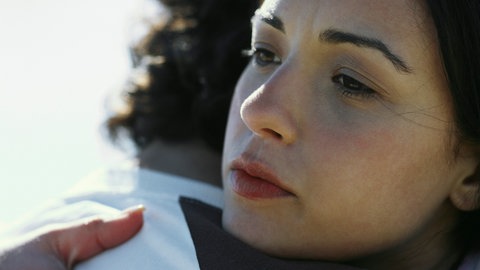 Gesicht einer Frau in Nahaufnahme, die eine Person umarmt