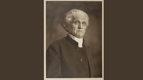 Portrait von Stefan George mit weißen Haaren, blickt von oben in die Kamera, 1928.