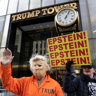 Ein Mann trägt eine Trumpmaske und einen orangen Gefängnisanzug bei einer Anti-Trump-Demonstration