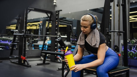 Frau im Fitnessstudio macht eine Pause mit Kopfhörern