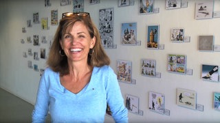 US-Karikaturistin Ann Telnaes vor einer Wand mit Zeichnungen