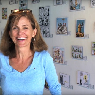US-Karikaturistin Ann Telnaes vor einer Wand mit Zeichnungen