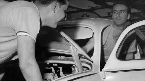 Ein italienischer Gastarbeiter (r) mit seinem deutschen Kollegen bei Arbeiten an einem VW-Käfer im Volkswagenwerk in Wolfsburg im Jahr 1962.