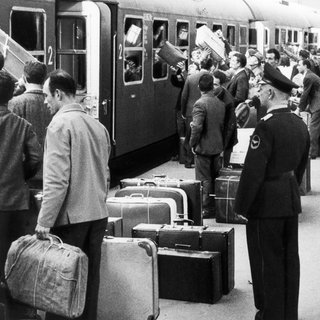 Italienische Gastarbeiter fahren im April 1963 vom Bahnhof Stuttgart mit einem Sonderzug zu den Parlamentswahlen nach Italien, stehen mit Gepäck auf dem überfüllten Bahnsteig.