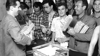 Eine Gruppe italienischer Gastarbeiter 1962 in Wolfsburg beim Kauf von Spaghetti.