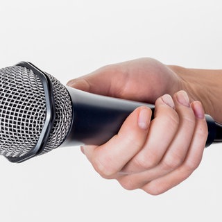 Eine Frau hält ein Mikrofon in der Hand. Interview und Umfrage. Symbolfoto.