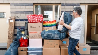 Ein Mann trägt Kartons aus einem Haus.