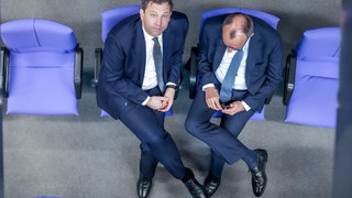 Bundesfinanzminister Lars Klingbeil und Bundeskanzler Friedrich Merz während einer Debatte auf den hinteren Rängen des Bundestages