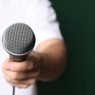 Mann hält Mikrofon für ein Interview. Symbolfoto.