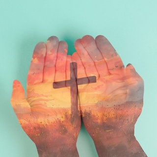 Christliches Kreuz in offenen gehaltenen Händen