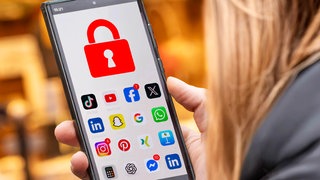 Schülerin mit Handy, auf dem die Social Media Apps mit einem Schloss  gesperrt sind