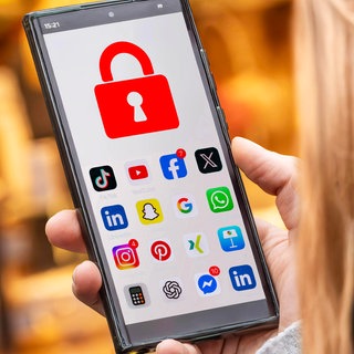 Schülerin mit Handy, auf dem die Social Media Apps mit einem Schloss  gesperrt sind