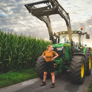 Landwirtin steht entschlossen vor einem Traktor