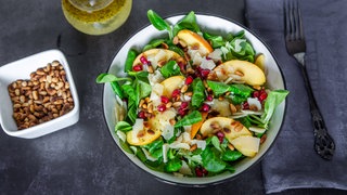 Eine Schüssel mit Salat, Pfirsischen und Granatapfelkernen
