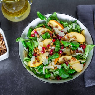 Eine Schüssel mit Salat, Pfirsischen und Granatapfelkernen