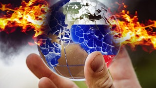 Eine Hand hält eine in Feuer stehende brennende und zerbrochene Weltkugel mit NATO-Logo und Russland-Flagge.