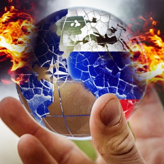 Eine Hand hält eine in Feuer stehende brennende und zerbrochene Weltkugel mit NATO-Logo und Russland-Flagge.