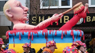 Auf dem Mottowagen liegt Putin in einer Badewanne voller Blut und schrubbt sich damit die Beine.