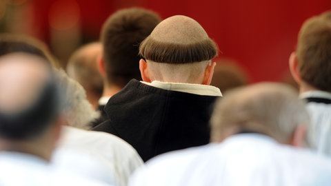 Ein Geistlicher mit Tonsur sitzt in der Priesterweihe