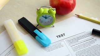 Ein leerer Lerntest für Schüler liegt mit einem Stift auf dem Tisch im Klassenzimmer.