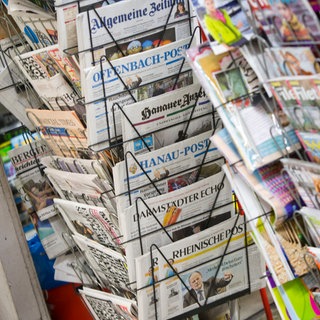 Tageszeitungen stecken in Frankfurt am Main an einem Zeitungsstand in Drehständern. 