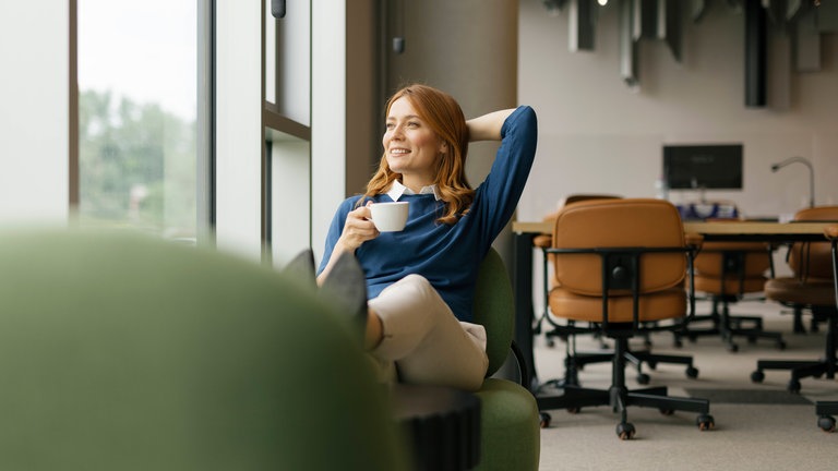 Frau genießt Kaffeepause in modernem Büroambiente. Modelvertrag, Symbolfoto.