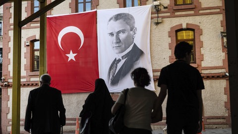 Die türkische Flagge wird neben einem Porträt von Mustafa Kemal Atatürk, dem Gründer der Türkischen Republik und ersten Präsidenten, gezeigt. 