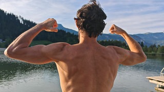 Mann mit nacktem Oberkörper zeigt seine Muskeln