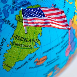 Eine US-Flagge steckt auf einem Globus im Bereich Grönland. 