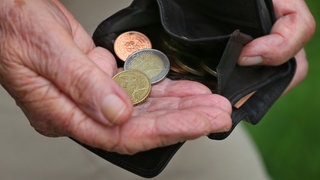 Eine Rentnerin hält einen Geldbeutel mit verschiedenen Euromünzen.