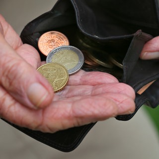 Eine Rentnerin hält einen Geldbeutel mit verschiedenen Euromünzen.