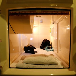 Schlafkabine mit eingebauten Fernseher in einem Kapselhotel. Fernseher, Klimaanlage und Licht werden von einer Konsole aus kontrolliert, die Kabine mit einer Sichtblende verschlossen. Japan. Archivfoto.