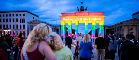 Das Brandenburger Tor wird in Regenbogenfarben illuminiert, wobei der Schriftzug „Berlin, Stadt der Freiheit“ zu lesen ist. Der Christopher Street Day in Berlin war am Vortag abgebrochen worden, nachdem ein Auto am Rande der Großveranstaltung in eine Menschenmenge gefahren war.